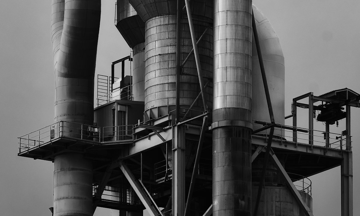 Towering steel industrial plant with pipes and gantries, in black and white